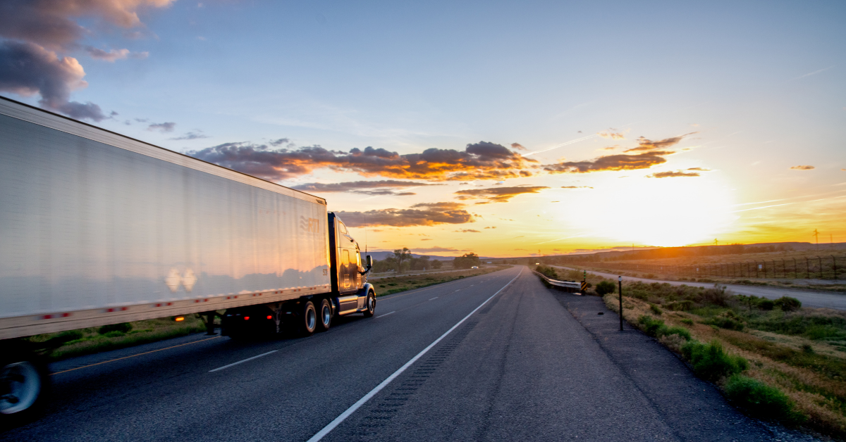 A long haul semi truck and trailer on a highway with a dramatic sky. 