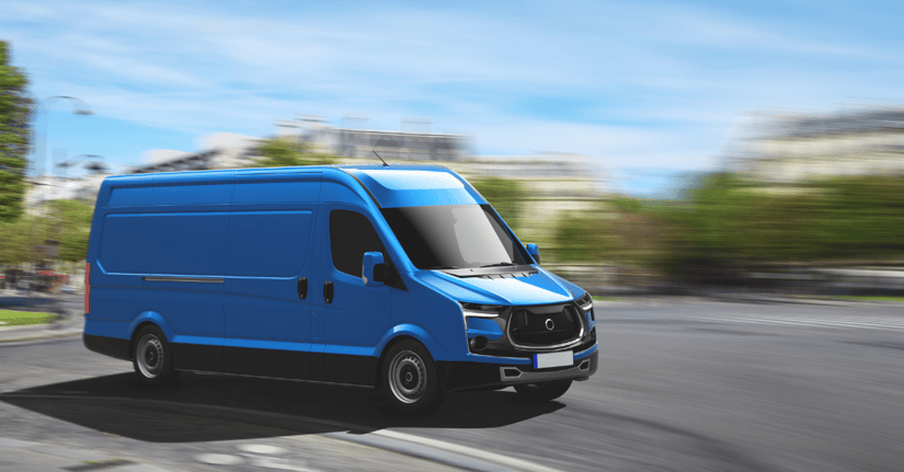 A blue delivery van speeding on a highway. 