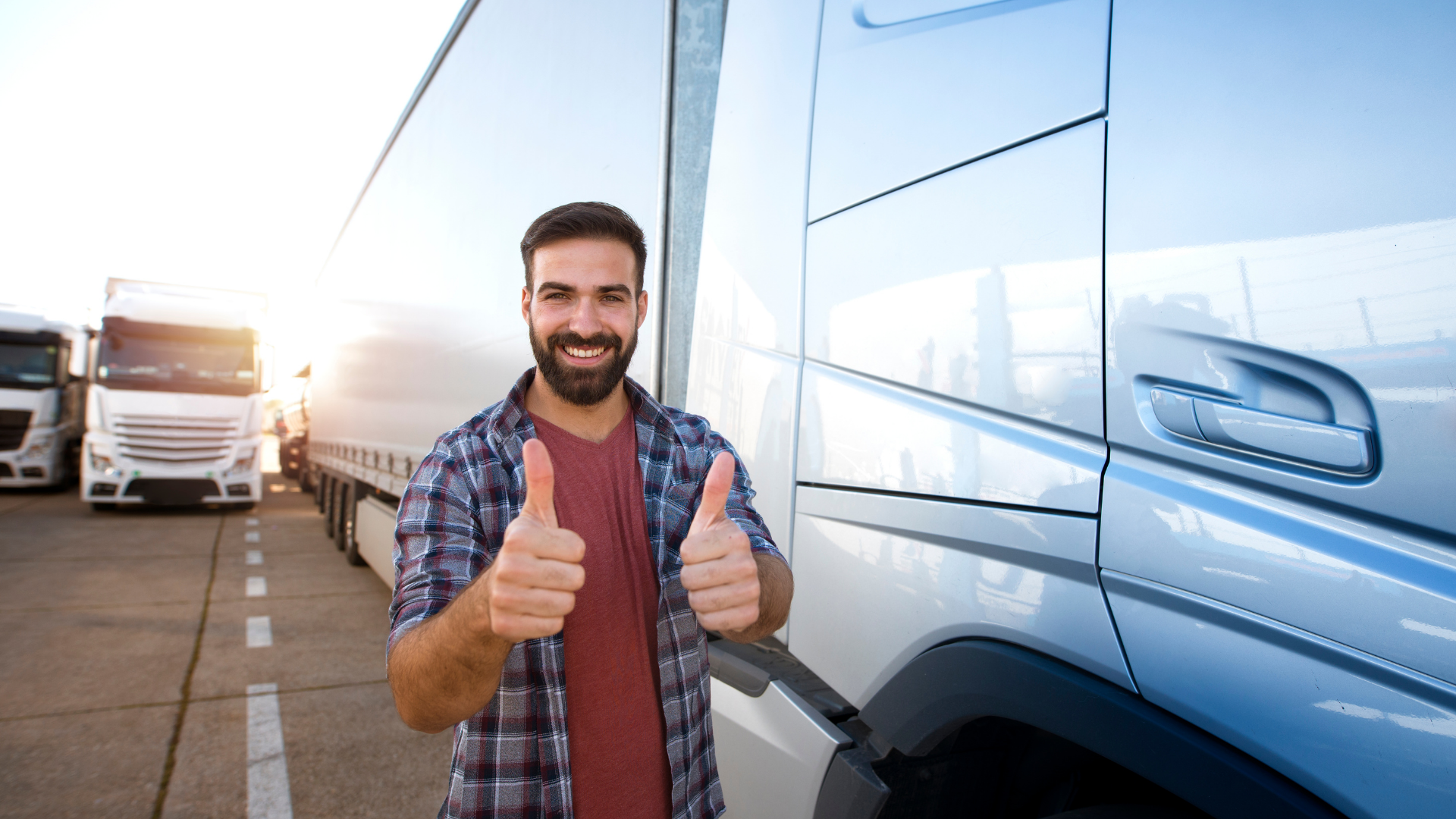 Happy truck driver with his thumbs up standing next to a blue truck.