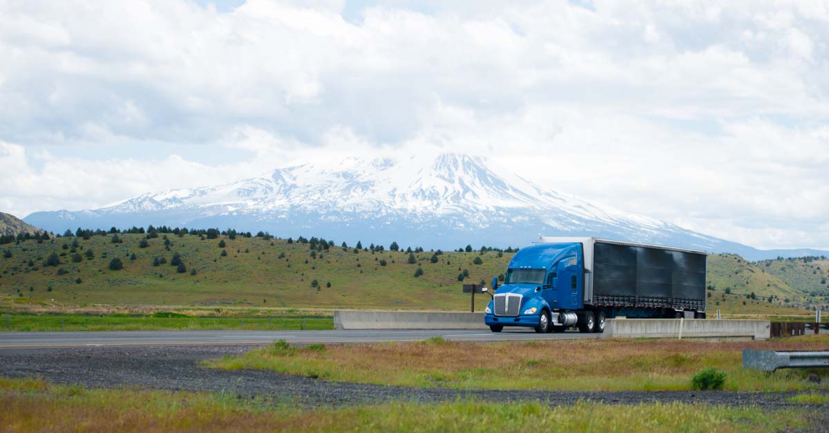 An 18-wheel truck and trailer driving on a highway in the mountains in the United States