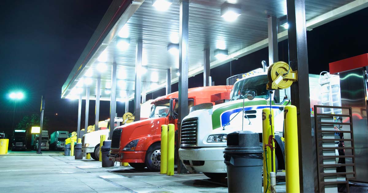 Three 18 wheel trucks refueling at a station at night