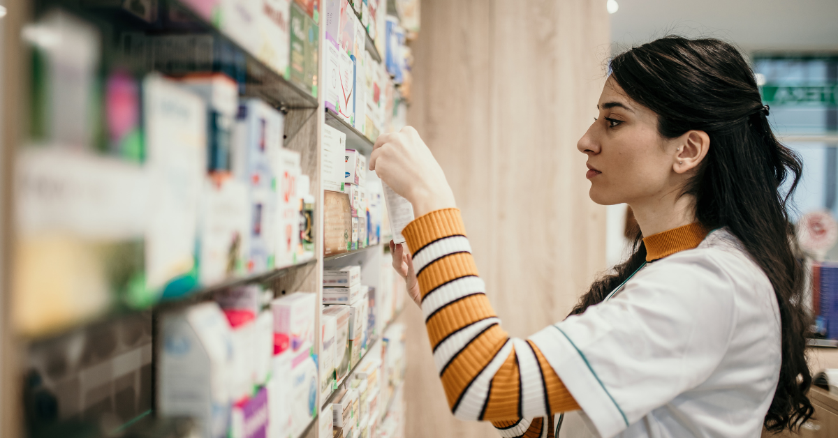 A pharmacist reads the expiration date on a box of prescription drugs.