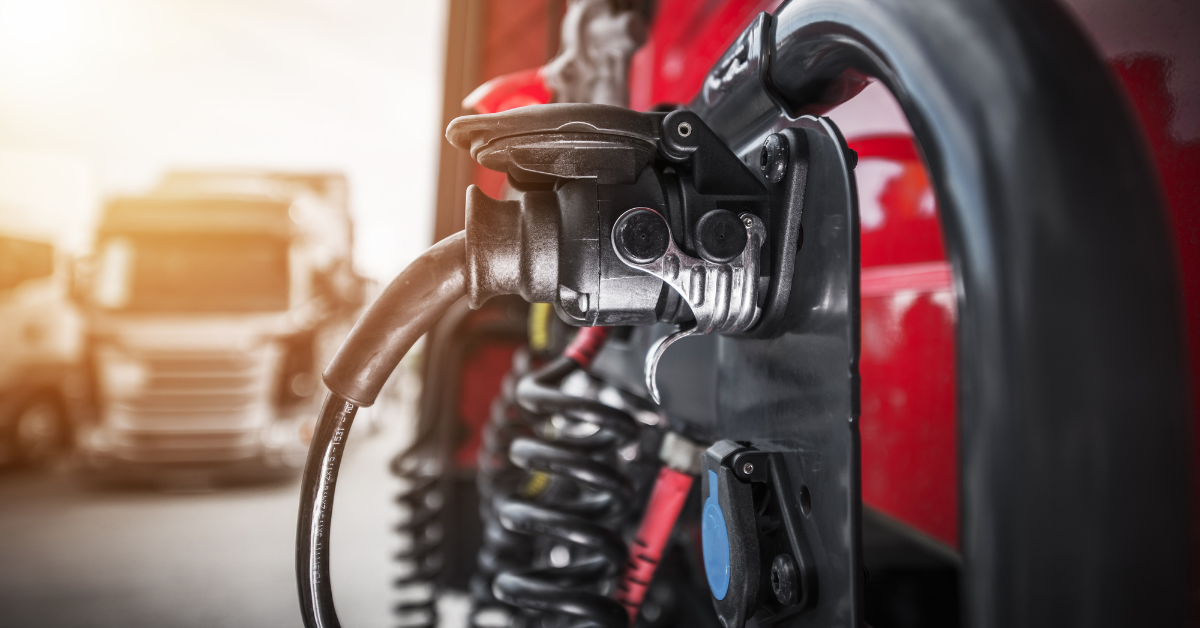 A truck trailer hookup charges an electric truck at a charging station. 